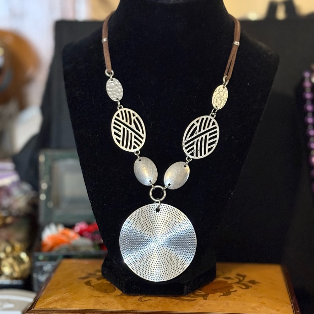 Silver Tone metal disk/bead and leather necklace. Unmarked. Looks better in real